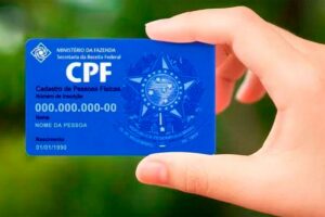 Uma mão segurando um CPF representando como regularizar cpf de pessoa falecida